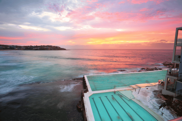 a pool with a body of water and a pink and orange sky