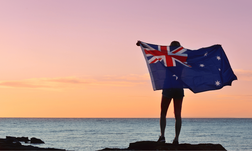 Moving to Australia - lady holding australian flag on a beach