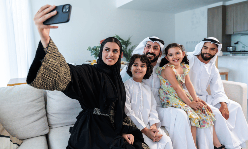 Emirati family in traditional clothing taking a cheerful selfie at home