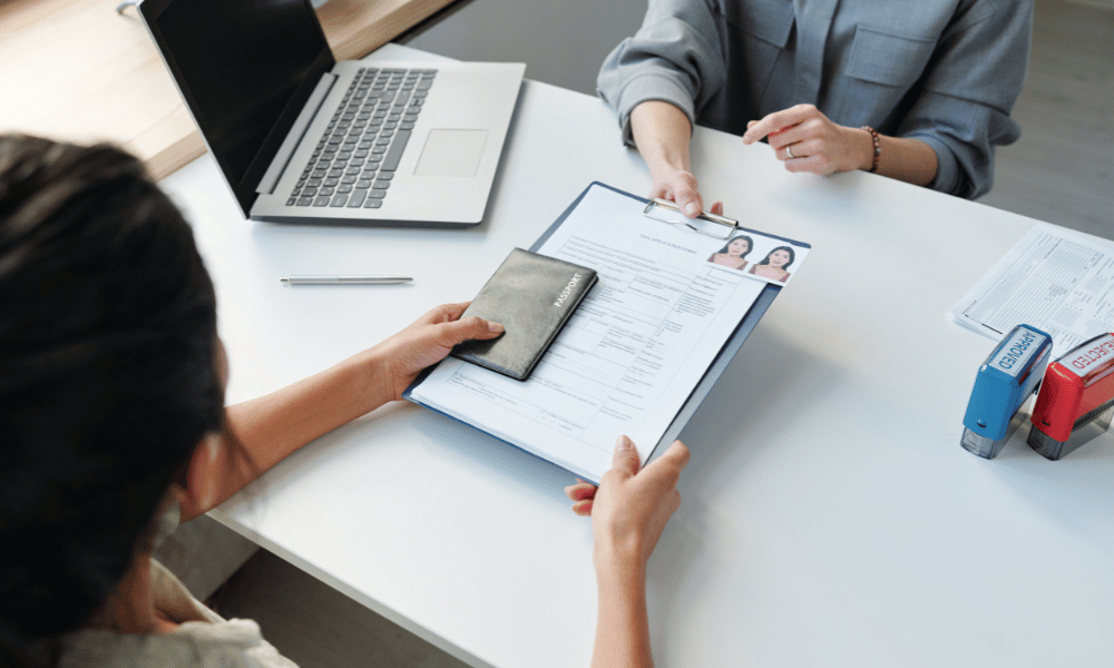 Person submitting passport and documents at an office desk