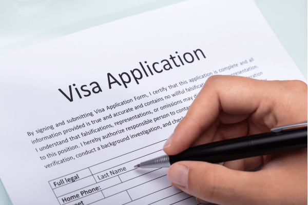Hand filling out a visa application form
